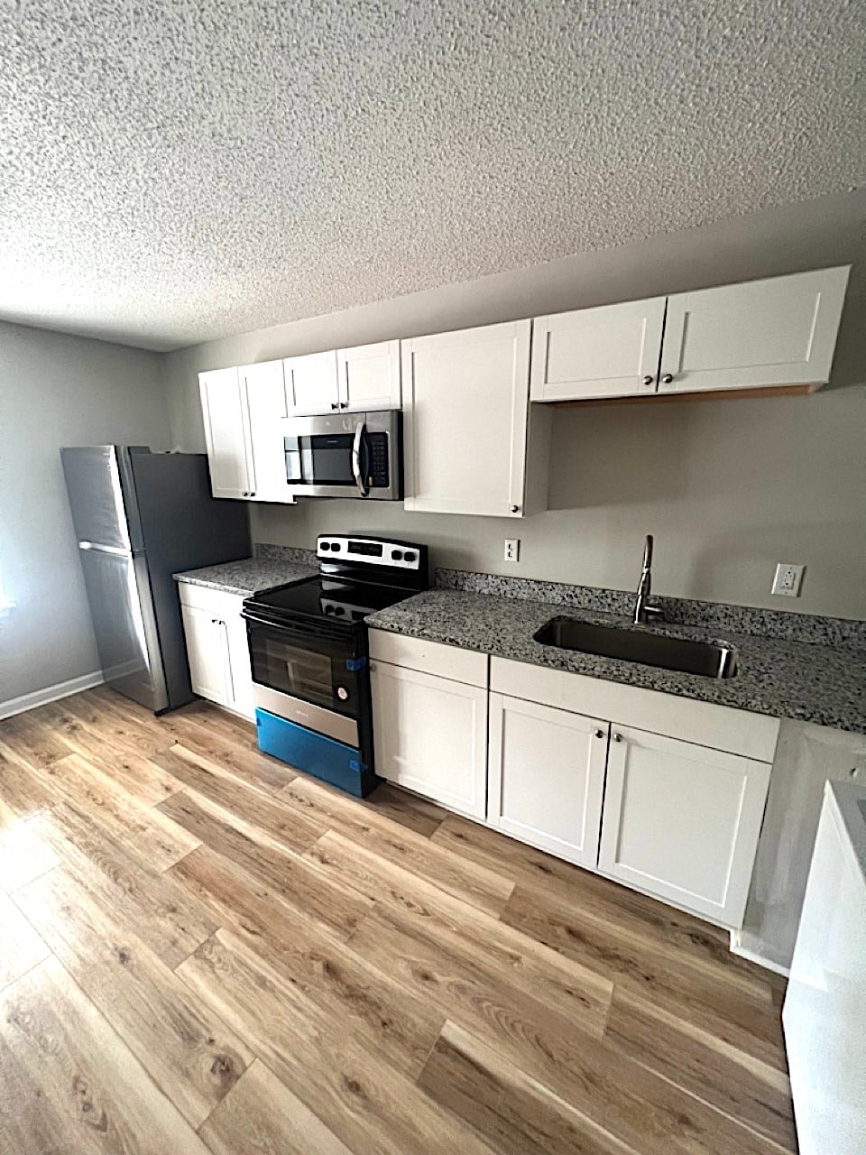 A kitchen with white cabinets and a black fridge.