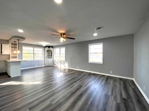 A spacious room with a ceiling fan and wooden flooring.