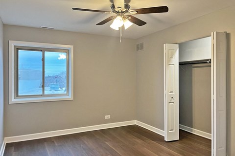 A room with a ceiling fan and a window overlooking a snowy landscape.