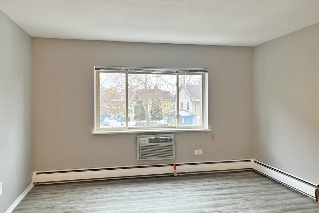 A room with a window and a heater on the floor.
