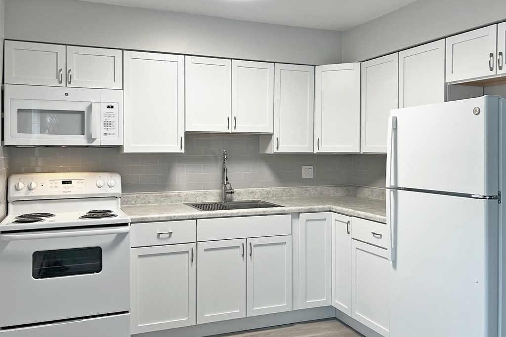 A kitchen with white appliances and cabinets.