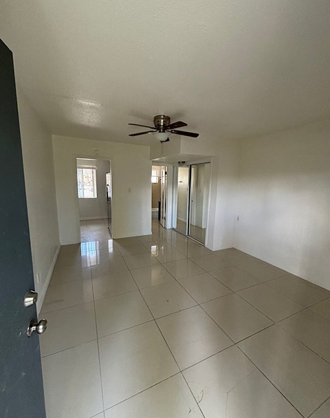 A spacious room with a ceiling fan and tiled flooring.