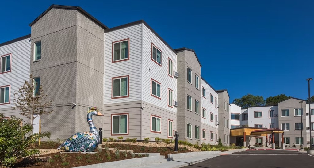 A large white building with a blue and white peacock statue in front.