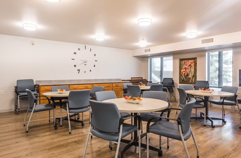 A room with tables and chairs and a clock on the wall.