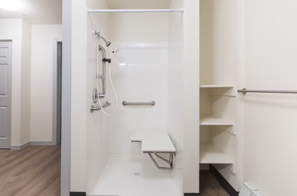 A white bathroom with a walk in shower and a bench.