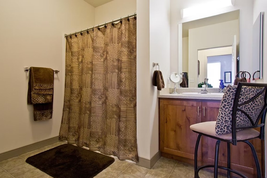 A bathroom with a brown shower curtain and a brown rug.