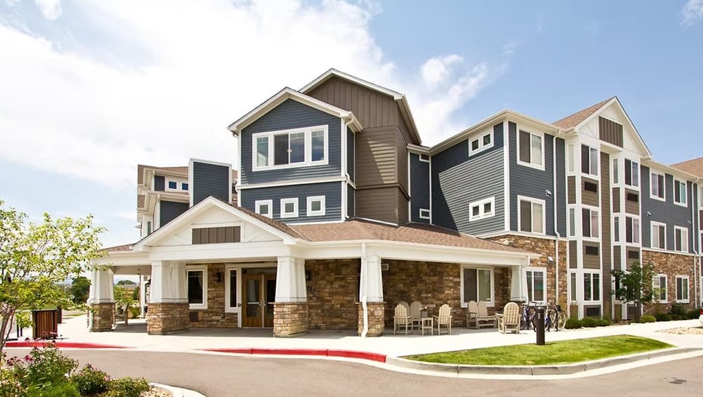 A large, modern building with a stone foundation and a covered walkway.