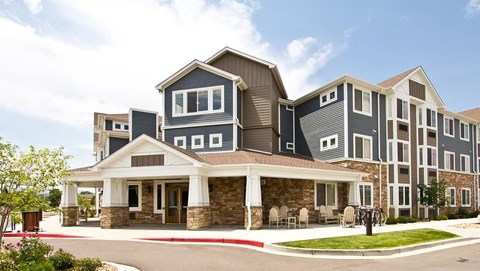 A large, modern building with a stone foundation and a covered walkway.