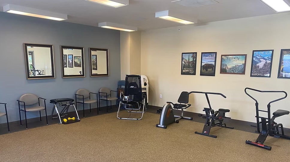 A gym room with exercise equipment and pictures on the wall.