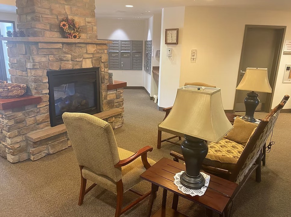 A living room with a stone fireplace and a chair.