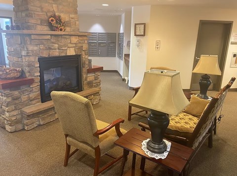 A living room with a stone fireplace and a chair.