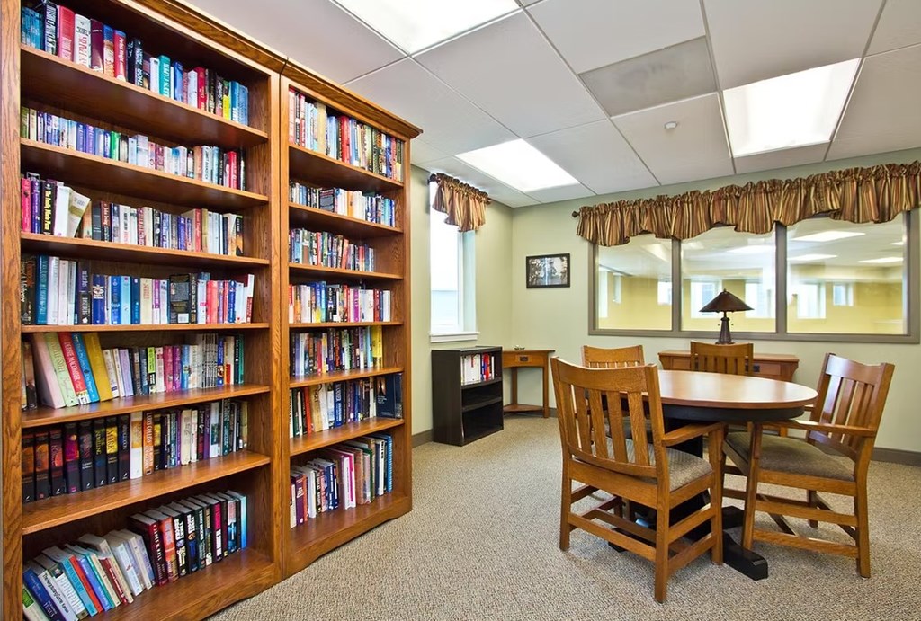 A room with a large bookshelf filled with books and a table with chairs.