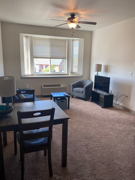 A room with a table, chairs, and a television.