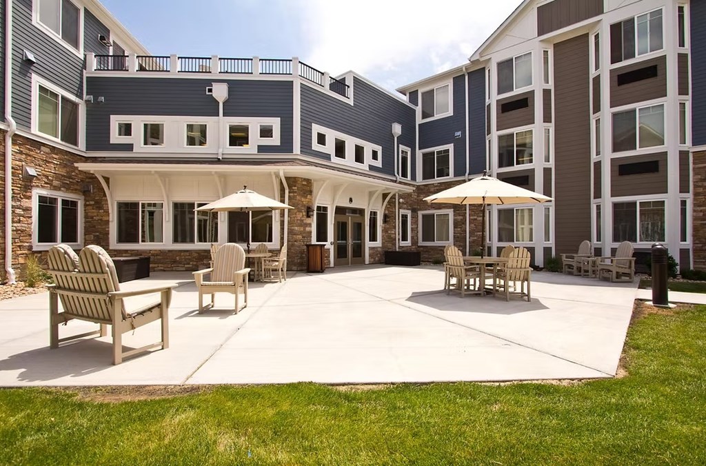 A large patio area with chairs and umbrellas in front of a building.