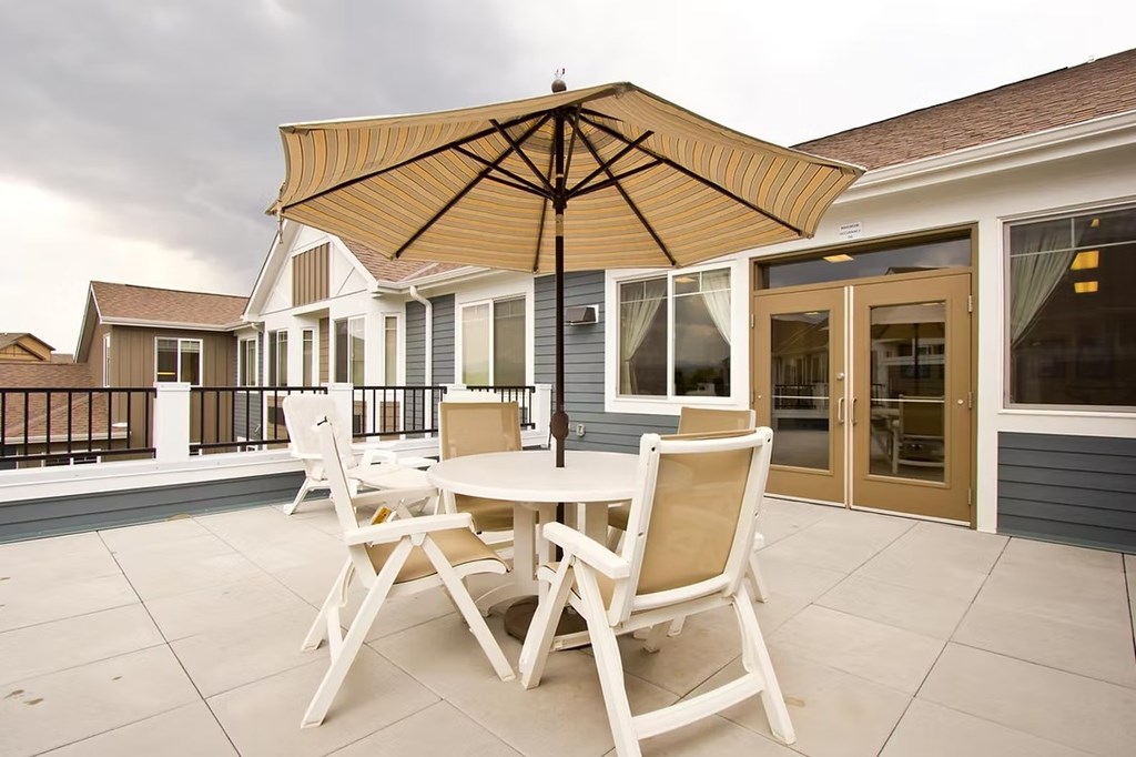A patio with a table and chairs under an umbrella.