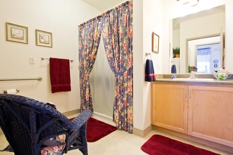 A room with a chair and a table with a vase of flowers on it.