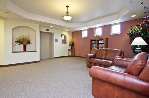 A living room with brown leather couches and a carpeted floor.