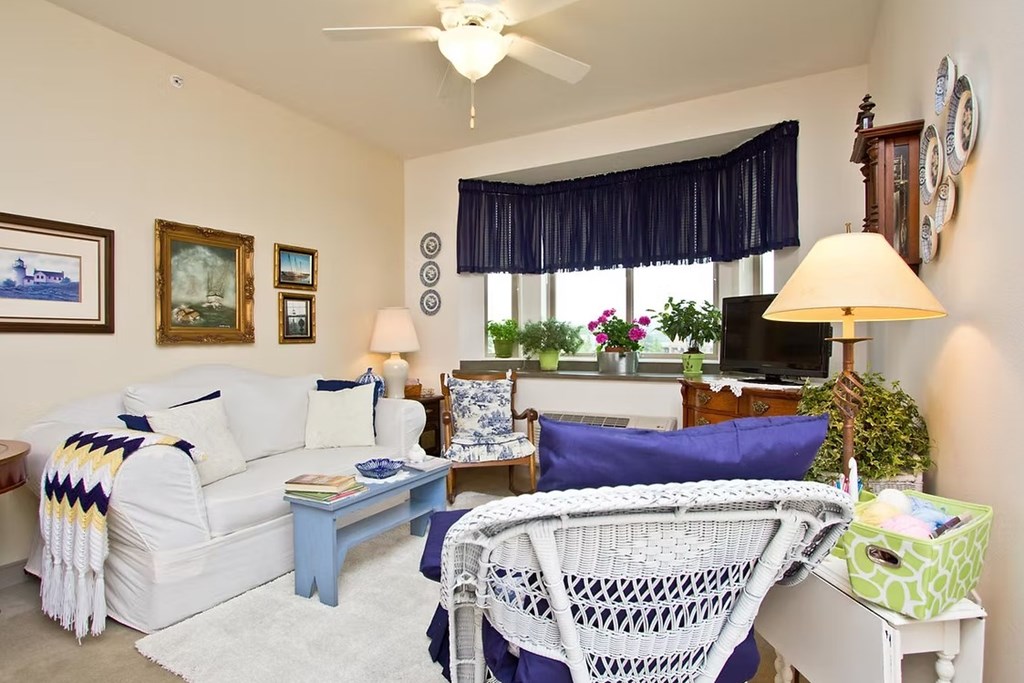 A living room with a white couch, a blue chair, and a white chair.