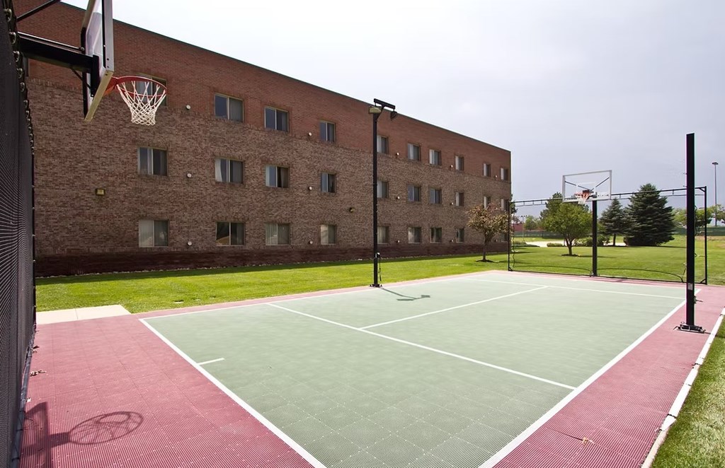 A basketball court is located in front of a brick building.