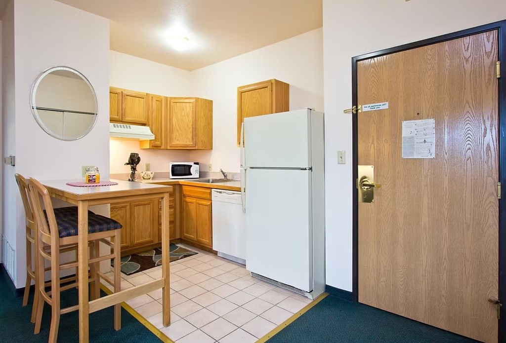 A kitchen with a table and chairs and a fridge.