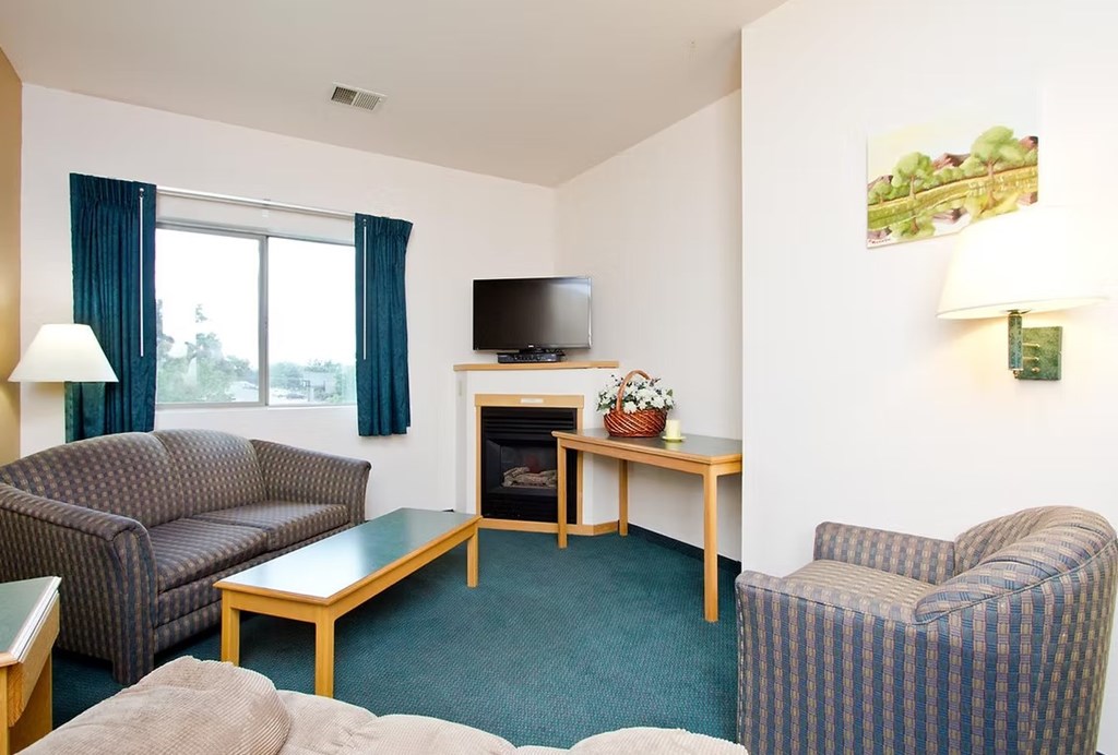 A living room with a grey couch, a wooden coffee table, and a television.