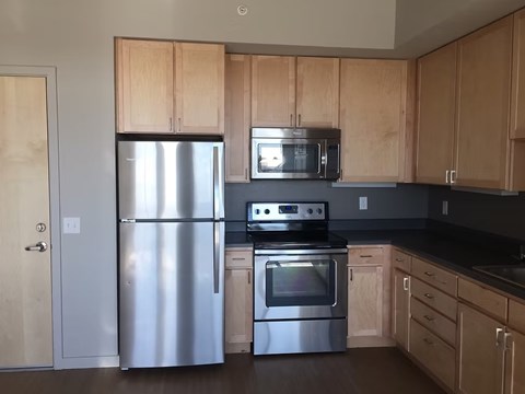 A kitchen with wooden cabinets and a stainless steel refrigerator.
