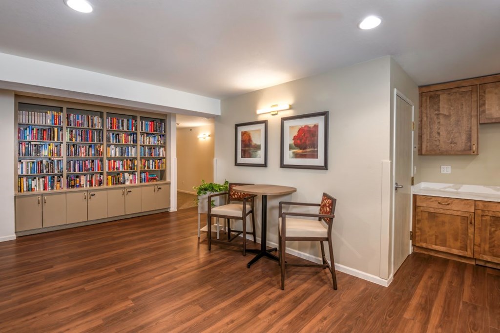 A room with a bookshelf filled with books and a table with two chairs.