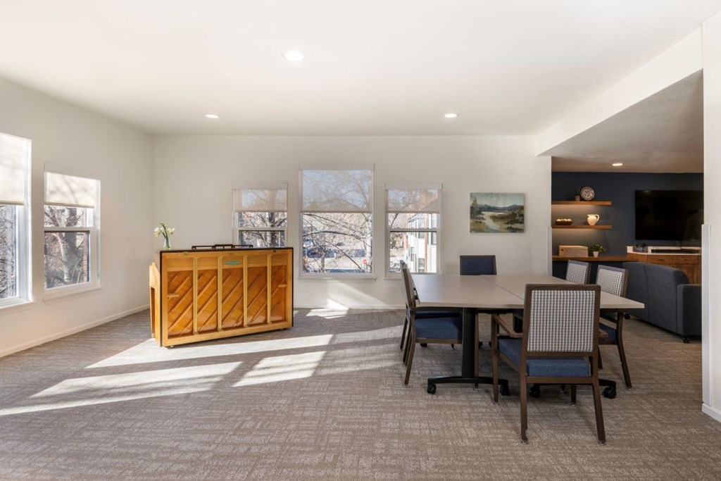 A room with a wooden cabinet, a table with chairs, and pictures on the wall.