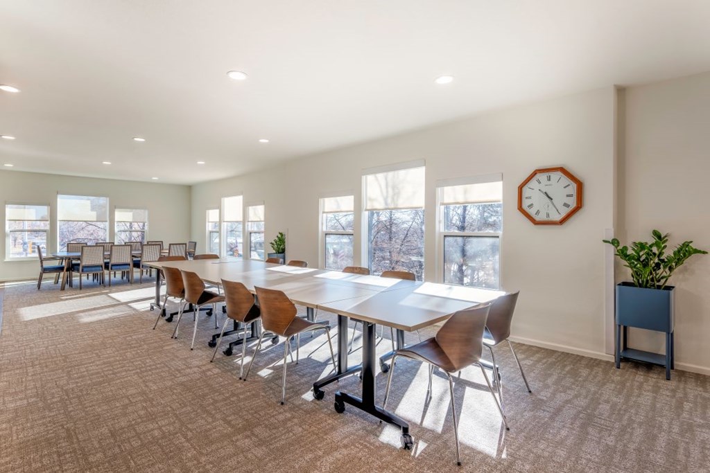 A conference room with a long table, chairs, and a clock on the wall.