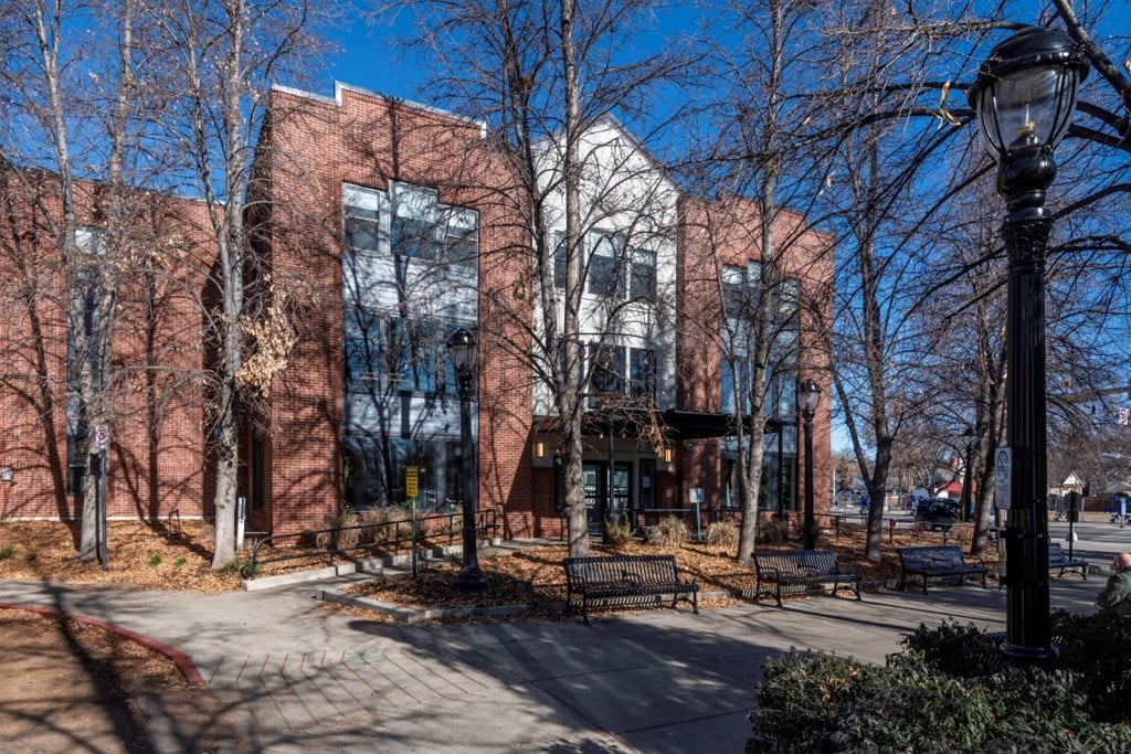 A street view of a building with a black lamp post in front.