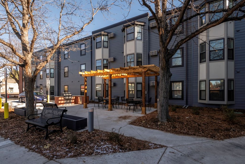 A modern building with a grey exterior and a wooden pergola in front.