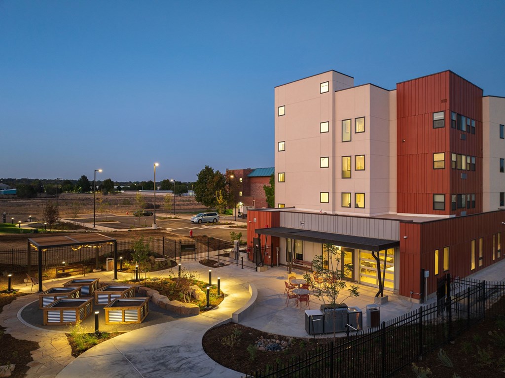 A modern building with a red and white exterior and a courtyard with a fountain.