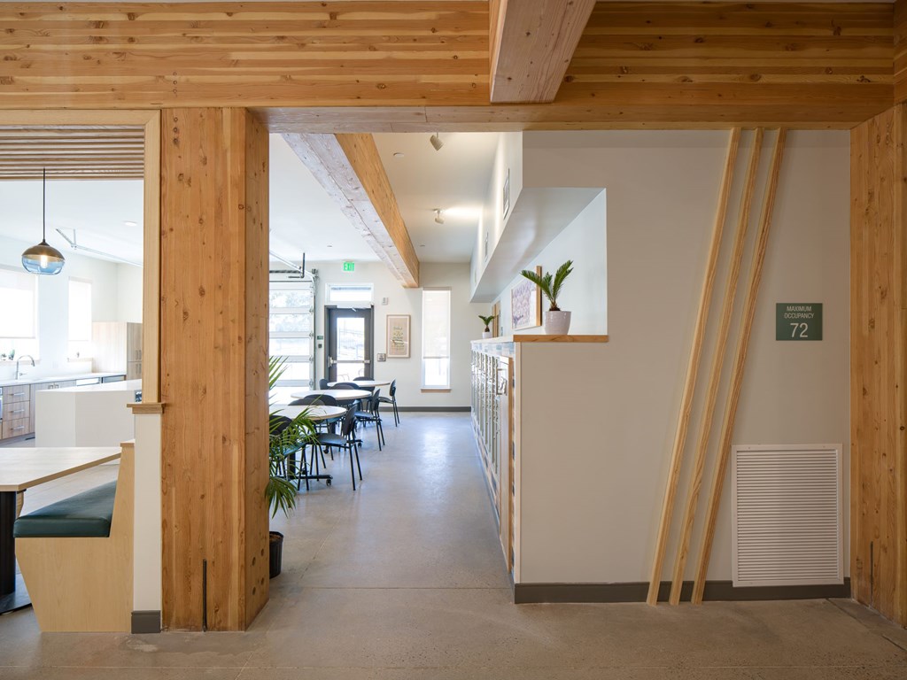 A long hallway with tables and chairs on the left and a door on the right.