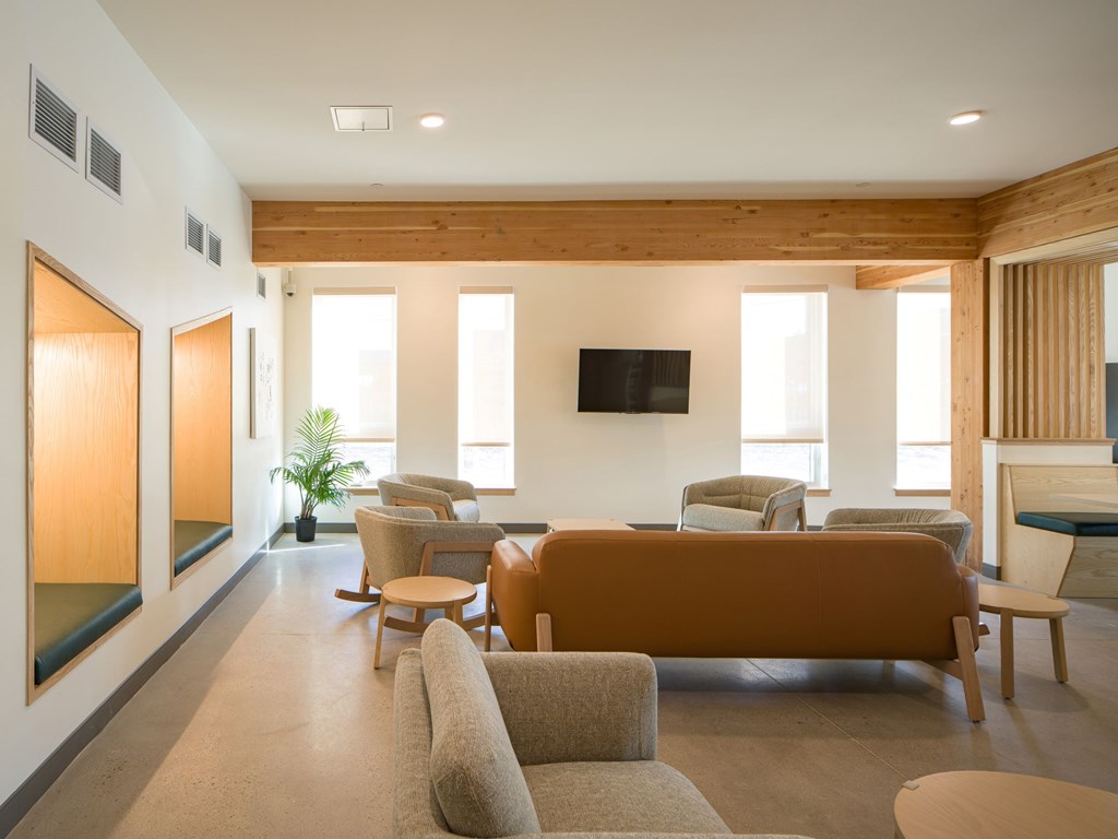 A living room with a brown couch and a television on the wall.