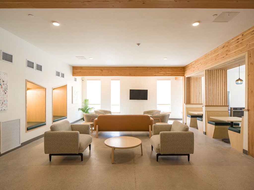 A living room with a brown couch and a television on the wall.