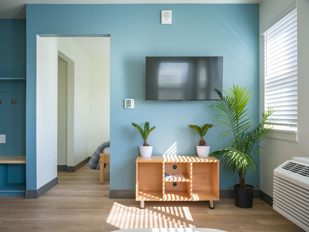 A room with a blue wall and a flat screen TV mounted on it.
