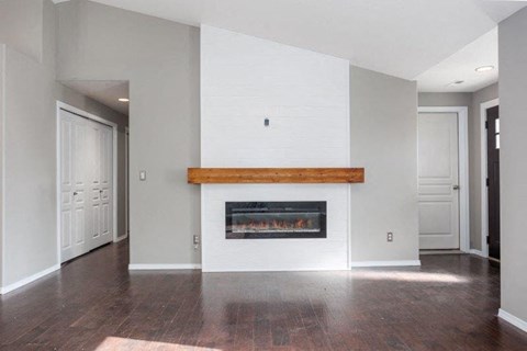 A modern living room with a fireplace and wood flooring.