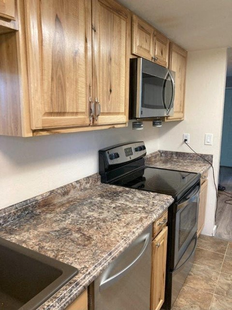 A kitchen with granite countertops and wooden cabinets.
