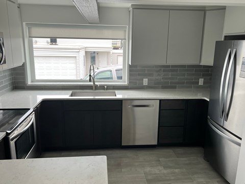 A kitchen with a sink, dishwasher, and refrigerator.