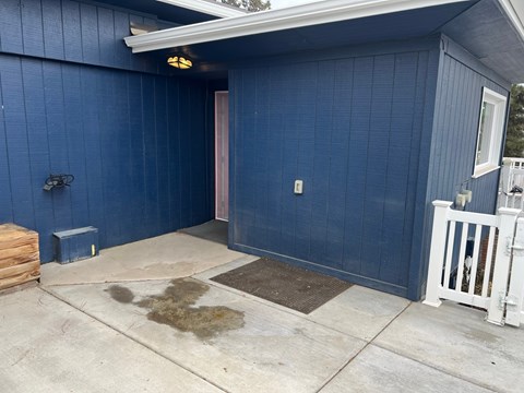 A blue building with a white fence and a brown door.