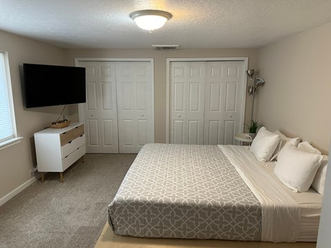 A bedroom with a bed, dresser, and television.
