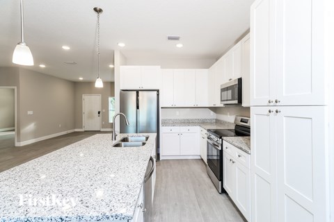 A modern kitchen with white cabinets and a granite countertop.
