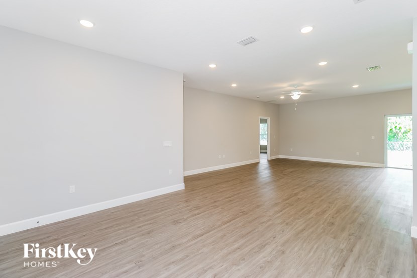 A spacious room with wooden flooring and white walls, branded with "FirstKey Homes".