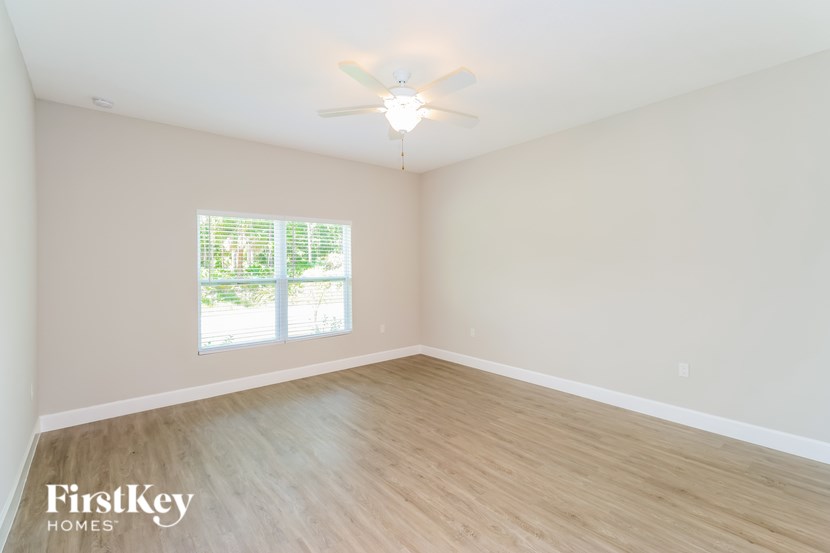 A room with a ceiling fan and a window with blinds.