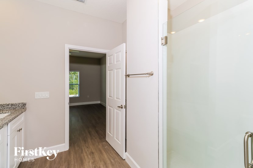 A white door is open to a room with a wooden floor.