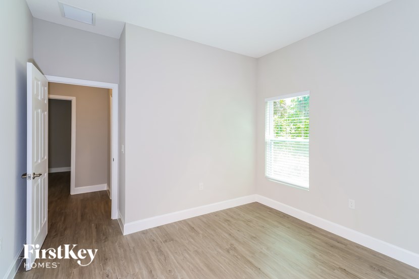 A room with a doorway leading to another room and a window with blinds.