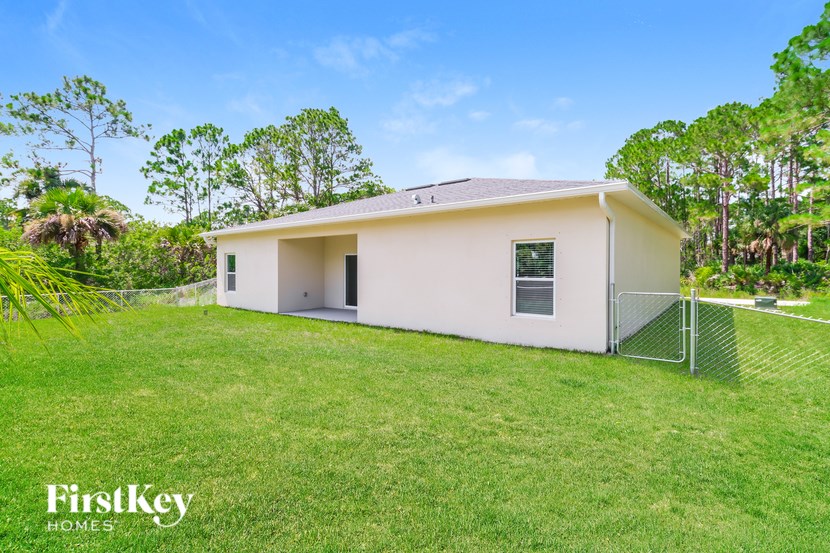 A small white house with a metal fence in front of it.