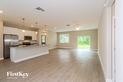 A spacious kitchen with a refrigerator, microwave, and a countertop with a window.