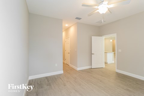 A spacious room with a ceiling fan and light fixture, and a doorway leading to another room.