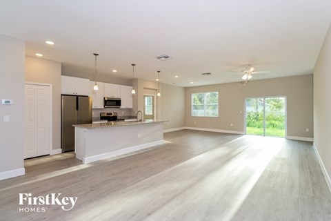 A spacious kitchen and living room with wooden floors and white walls.